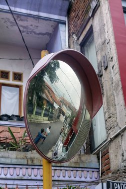 Bir dışbükey trafik aynası, insanların yürüdüğü ve binaların arka planda olduğu bir sokak sahnesini yansıtır ve benzersiz bir perspektif yaratır.