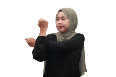 Başörtüsü takan genç Müslüman bir kadın ısınma egzersizi için kollarını uzatıyor.