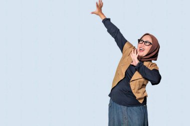 Neşeli bir Müslüman kadın, hayat tarzı ve moda temaları için mükemmel enerjik bir pozla mutluluğu ifade ediyor.