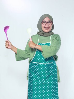 Gülümseyen kadın aşçı mutfakta kepçe tutuyor, lezzetli yemekler pişirmeye hazır.