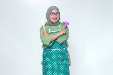 Neşeli kadın aşçı elinde renkli yemek kaşıklarıyla yemek hazırlamaya hazır.