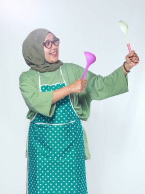 Mutlu kadın aşçı elinde renkli mutfak gereçleri, yemek için hazır.