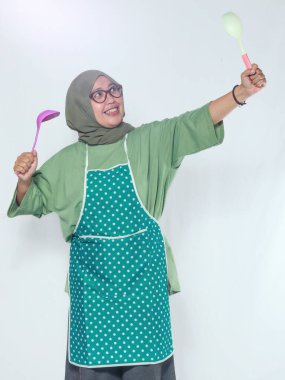 Yemek pişirme pozisyonunda kepçe tutan mutlu kadın şef, yemek hazırlamaya hazır.