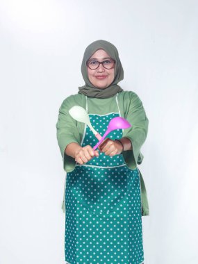 Gülümseyen kadın şef, elinde kepçelerle, lezzetli yemekler pişirmeye hazır.