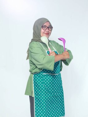 Kendine güveni tam aşçı bir kadın, elinde mutfak aletleri, gülümseyerek pişirmeye hazır.