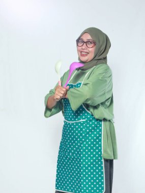 Mutlu kıdemli kadın aşçı elinde yemek aletleri tutuyor, lezzetli yemekler hazırlamaya hazır.