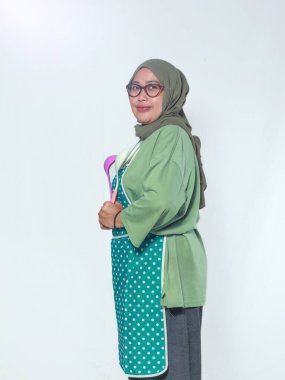 Kendine güvenen kıdemli kadın şef mutfakta sıcak bir gülümsemeyle mutfak aletleri tutuyor.