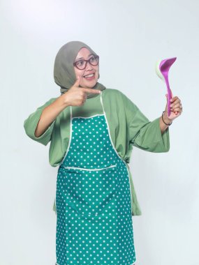 Mutfakta mutfak malzemelerini tutarken gülümseyen kıdemli kadın şef.