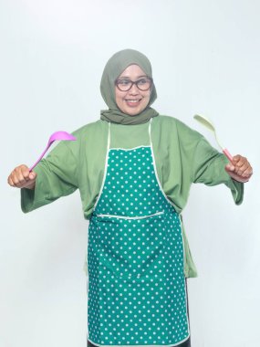 Evde mutfak aletleri tutarken gülümseyen kıdemli kadın şef.