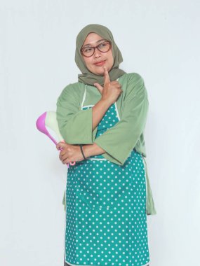 Mutfak aletlerini yaratıcı bir pozda tutan düşünceli kıdemli kadın şef.