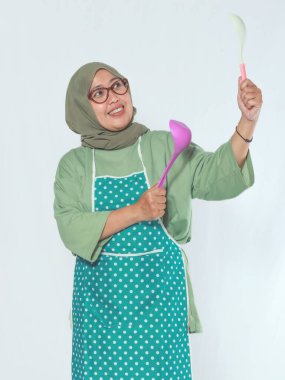 Mutfak gereçleriyle mutlu bir şekilde yemek pişiren neşeli son sınıf kadını.