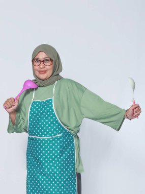 Önlüklü, yemek pişirmeye hazır, mutlu Müslüman bir kadın.