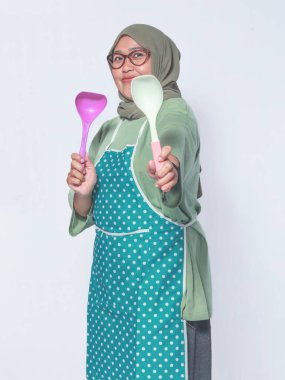 Mutfak aletleri taşıyan neşeli Müslüman kadın, lezzetli yemekler pişirmeye hazır.