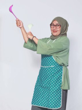 Yemek pişirirken önlük giymiş neşeli Müslüman kadın.