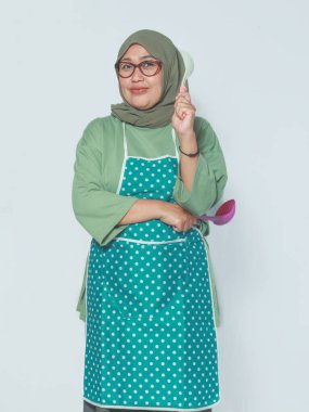 Mutfak aletleriyle poz veren Müslüman kadın, neşe ve güveni dile getiriyor