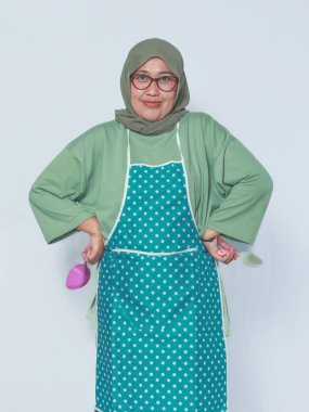 Kendine güvenen Müslüman kadın mutfak malzemeleriyle poz veriyor, yemek yapmaya hazır.