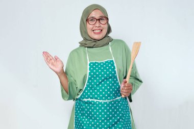 Ev aşçısı elinde tahta bir kaşıkla gülümsüyor, lezzetli yemekler pişirmeye hazır.