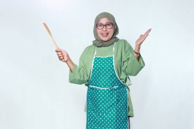 Müslüman ev aşçısı elinde tahta bir Spatula tutarken gülümsüyor