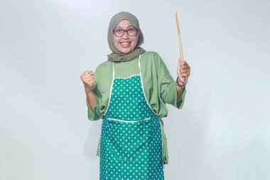 Ahşap bir spatula tutan kendine güvenen kadın şef, tutku ve hünerle yemek yapmaya hazır.