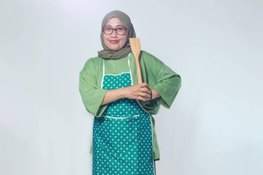 Ahşap bir spatulayla yemek pişirmeye hazır, kendinden emin bir kadın şef.