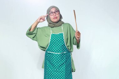 Düşünceli kadın aşçı ahşap bir Spatula tutuyor.