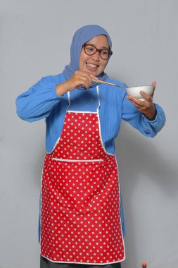 Neşeli Müslüman kadın ev yapımı lezzetli bir Asya yemeği pişiriyor ve eğleniyor.