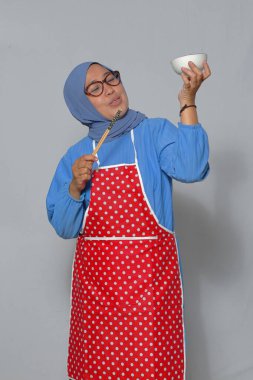 Mutfakta ev yapımı Asya yemeğinin tadını çıkaran neşeli Müslüman kadın.