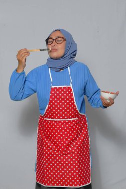 Müslüman kadın, mutfakta çubuklarla ev yapımı Asya yemeklerini tadıyor.