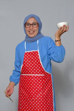 Elinde boş bir kâse ve yemek çubuğu tutan gülümseyen kadın, mutfak temaları için mükemmel.