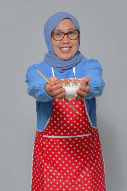 Yemek çubuklarıyla bir kase yemek sunan mutlu bir kadın. Mutfak temaları için mükemmel.