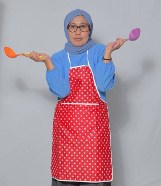 Ne pişireceğine karar verirken elinde mutfak gereçleri tutan kafası karışmış Müslüman kadın.