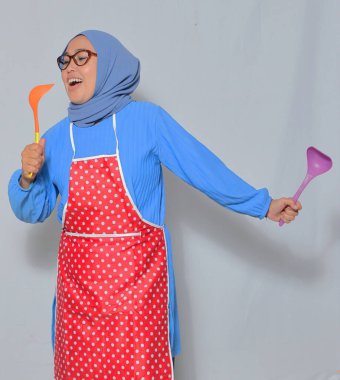 Mutlu kıdemli şef kepçelerle şarkı söylüyor, eğlenceli bir yemek anının tadını çıkarıyor.