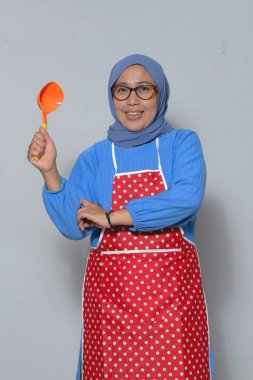 Yemek kepçesini tutan kıdemli kadın şef lezzetli yemekler hazırlamaya hazır.