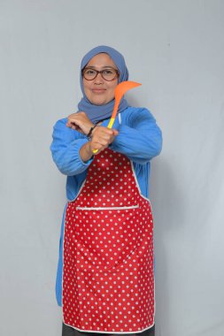 Kendine güveni tam yaşlı bir kadın yemek pişirme aletini kararlı bir şekilde tutuyor.