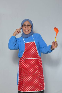 Gülümseyen Müslüman Şef Ladle 'ı tutuyor ve başını işaret ediyor.