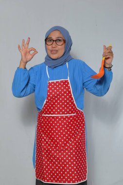 Kendine güvenen kadın aşçı kepçeyi aşçılığa hazır tutuyor.