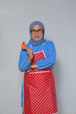 Kendine güvenen aşçı kadın aşçı kepçesini tutuyor.