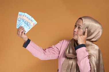 Endonezya Rupia 'sının parasını elinde tutan kendine güvenen kadın, mali başarı ve karar verme yeteneği gösteriyor.