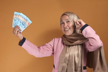 Endonezya parası elinde tutan mutlu kadın, finansal özgürlük ve başarı gösteriyor.