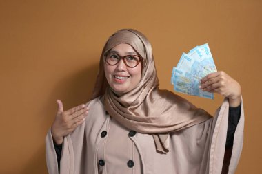 Endonezya Rupisi 'ni elinde tutan ve gösteren neşeli Müslüman kadın, finansal başarıyı ve zenginliği simgeliyor.