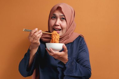 Müslüman kadın yemek çubuklarıyla hazır eriştenin keyfini çıkarıyor.