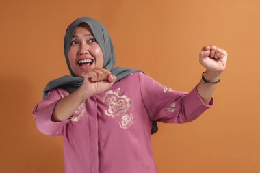 Heyecanlı Müslüman kadın küçük zaferimizi neşeli bir yumruk hareketiyle kutluyor.