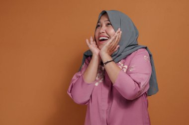 Heyecanlı Müslüman kadın büyük bir gülümsemeyle neşe ve mutluluk ifade ediyor.