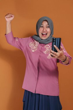 Neşeli Müslüman kadın heyecanlı bir ifadeyle selfie çekiyor, mutlu yaşam tarzı ve iletişim konsepti trend oluyor