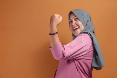 Müslüman kadın kendine güven ve neşe dolu güçlü bir ifade sergiliyor.