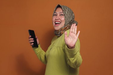 Hayat tarzı konsepti için telefonu tutarken gülümseyen mutlu Müslüman kadın