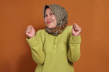 Heyecanlı Müslüman kadın çevrimiçi zaferi neşeli bir ifadeyle kutluyor.