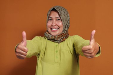 Mutlu Müslüman kadın, büyük bir gülümseme ve neşeyle iki baş parmak kaldırıyor.