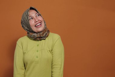 Mutlu Müslüman kadın neşeli bir gülümseme ve neşeli bir ifadeyle yukarı bakıyor.