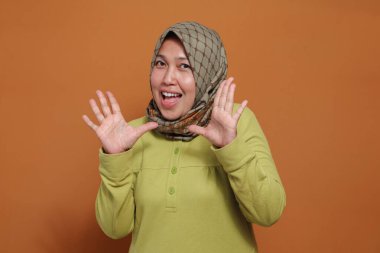 Neşeli Müslüman kadın neşeli enerji ve ifadeyle komik surat yapıyor.